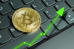 Bitcoin on computer laptop for investing and happiness for financial and business gain concept.  Green up arrow rising prices.