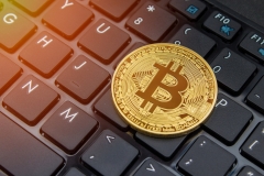 Bitcoin trading on laptop buying and selling online.  Physical bitcoin on laptop keys.