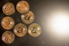 Bitcoins on table with high contrast and bright light with dark grey background.  Empty copy space with area for text.