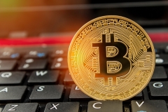 Golden physical bitcoin set on keyboard keys on laptop for internet trading remote investment and purchase of crypto currency.  Copy space for wording.