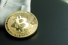 Learn how to invest on crypto exchange.  Physical golden bitcoin on white cloth.