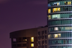 Highrise building apartment windows at night.  Purple skies and warm lights.