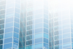 White copy space flare over modern building facade in glass and metal.  New construction highrise buildings for business and finance.