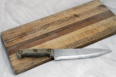 Wooden knife on grainy old fashioned cutting board with empty copy space for words.