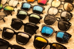 Sunglasses apparel in market shop with big discounts on eyewear and a huge sale.  Blurred edges with focus on blue glasses for outdoors.